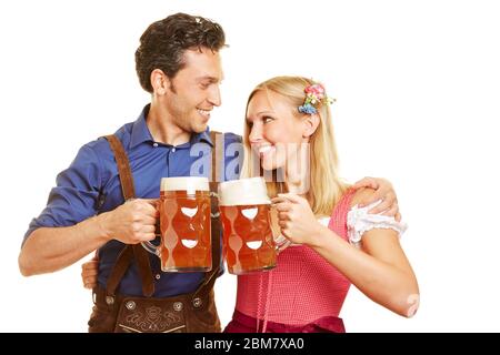 Lächelndes Paar trinkt Bier in Dirndls und Lederhosen zum Oktoberfest Stockfoto