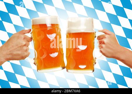 Zwei Hände klirken vor einer bayerischen Flagge ein Glas Bier Stockfoto