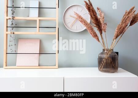 Retro moderne Dekoration Wand im Wohnzimmer mit Pastellfarben, weiße Uhr und Regal, moderne Vase mit Pampas Gras skandinavischen Interieur Stockfoto