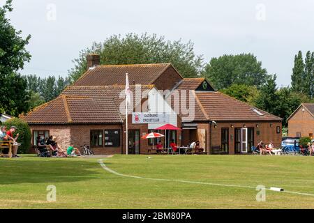 Leute, die ein Dorf Cricket Spiel außerhalb Old Basing Cricket Pavillon, Hampshire, Großbritannien Stockfoto