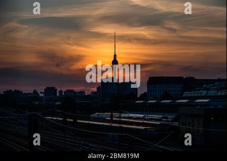 Berlin, Deutschland. Mai 2020. Die Sonne geht hinter dem Fernsehturm unter. Im Vordergrund fährt ein Vorstadtzug. Kredit: Christophe Gateau/dpa/Alamy Live News Stockfoto