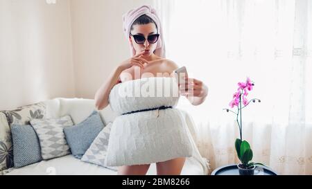 Pillow Challenge zu Hause während der Quarantäneisolation des Coronavirus pandemic. Junge Frau, die Selfie trägt Kissen Stockfoto