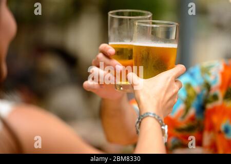 Ein glückliches, ethnisches Touristenpaar, das gemeinsam im Restaurant Bier trinkt Stockfoto