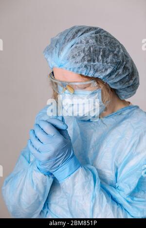 Betende müde Arzt. Müde Krankenschwester im Krankenhaus. Der Kampf gegen die Krankheit, Viren. Ein Arzt, eine Krankenschwester, die über die Behandlung einer Krankheit nachdenkt Stockfoto
