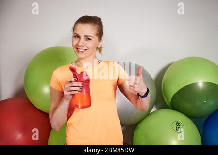 Schlanke sportliche junge Frau in Sportbekleidung mit Wasserflasche im Fitnessclub. Stockfoto