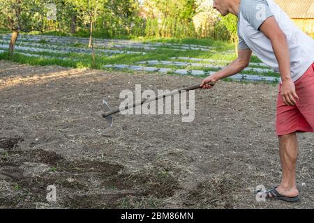 Casual männlich arbeitet mit Hacke im Garten zu Hause Stockfoto