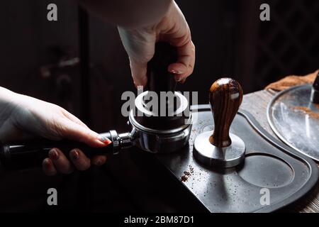 Barista drücken gemahlenen Kaffee in portafilter mit einem Stampfer. Stockfoto