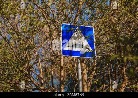 Straßenschild künstliche Rauheit unter den Bäumen, auf denen die Blätter blühen. Gegen den blauen Himmel Stockfoto