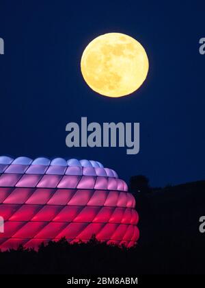 München, Deutschland. Mai 2020. Der Vollmond erhebt sich hinter der beleuchteten Allianz Arena. Quelle: Peter Kneffel/dpa/Alamy Live News Stockfoto