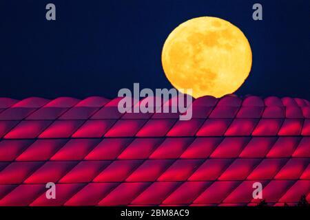 München, Deutschland. Mai 2020. Der Vollmond erhebt sich hinter der beleuchteten Allianz Arena. Quelle: Peter Kneffel/dpa/Alamy Live News Stockfoto