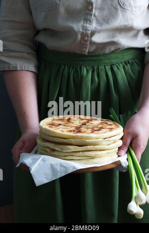 Frau hält in den Händen traditionelle in verschiedenen Ländern Kuchen gefüllt mit Käse und Kräutern und frischem Knoblauch. Stockfoto