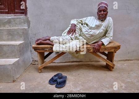 Porträt eines Nigerianers mittleren Alters, der auf einer Holzbank liegt. Stockfoto