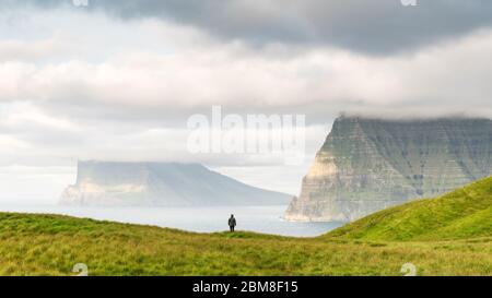 Lonely Tourist in der Nähe von kleinen See schaut auf nebligen Inseln im Atlantik von kalsoy Island, Färöer, Dänemark. Landschaftsfotografie Stockfoto