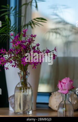 Innenausstattung: Wohnecke mit rosa Rose, getrocknetem Kürbis, Glasvase mit Wildblumen und herzförmigem Stein Stockfoto