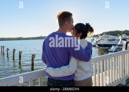 Rückansicht des jungen multi ethnischen Paar küssen sich gegenseitig am Pier im Freien Stockfoto