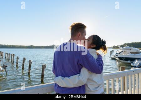 Rückansicht des jungen multi ethnischen Paar küssen sich gegenseitig am Pier im Freien Stockfoto