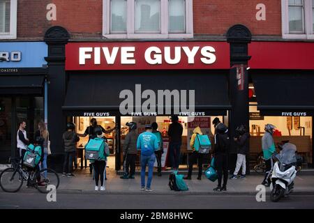 London, Großbritannien, 7. Mai 2020: In der Clapham High Street, in einer Filiale der fünf Jungs Burger-Kette, sammeln viele Lieferfahrer und Kunden, die Online-Bestellungen sammeln, außerhalb und soziale Distanzierungsregeln werden nicht strikt eingehalten. Anna Watson/Alamy Live News Stockfoto