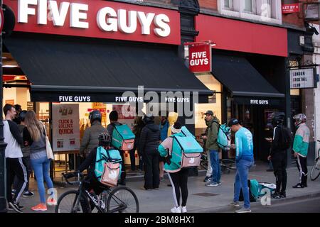 London, Großbritannien, 7. Mai 2020: In der Clapham High Street, in einer Filiale der fünf Jungs Burger-Kette, sammeln viele Lieferfahrer und Kunden, die Online-Bestellungen sammeln, außerhalb und soziale Distanzierungsregeln werden nicht strikt eingehalten. Anna Watson/Alamy Live News Stockfoto