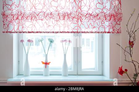 Gemütliches Innenraumkonzept in Pastellfarben. Drei Vasen mit Blumen auf einer Fensterbank. Stockfoto