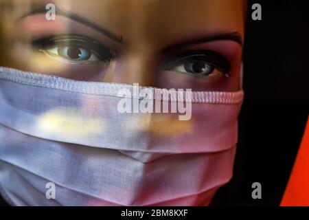 Bukarest, Rumänien - 07. Mai 2020: Eine weiße Baumwollmaske wird auf einer Schaufensterpuppe im Fenster eines Bekleidungsladens angezeigt. Stockfoto