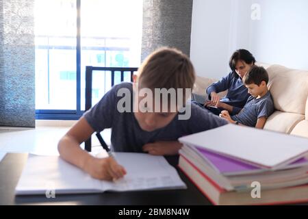 Kinder lernen zu Hause. Mutter hilft ihrem Sohn bei Hausaufgaben und arbeitet online mit einem Laptop. Online lernen, arbeiten, Fernstudium Stockfoto