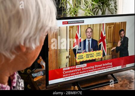 Der stellvertretende Premierminister Dominic Raab gibt das Coronavirus Downing Street Briefing, beobachtet von einem Zuschauer. "Bleib zu Hause, rette den NHS, rette Leben" Banner. Stockfoto