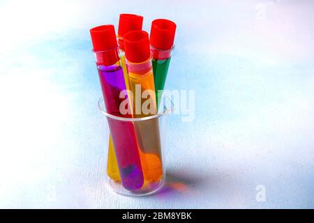Reagenzgläser in einem Rack mit regenbogenfarbenen Lösungen. Laborgeräte. Stockfoto
