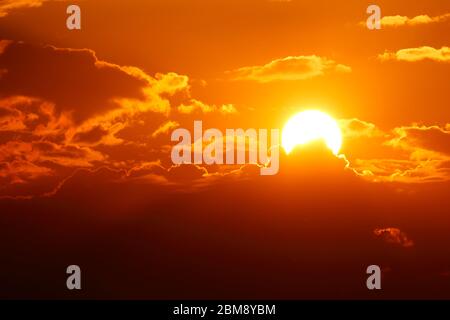 Die Sonne, die sich teilweise in Wolken über Leeds versteckt, während sie zu untergehen beginnt. Stockfoto