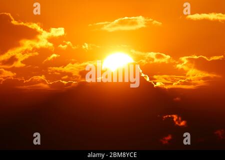 Die Sonne, die sich teilweise in Wolken über Leeds versteckt, während sie zu untergehen beginnt. Stockfoto
