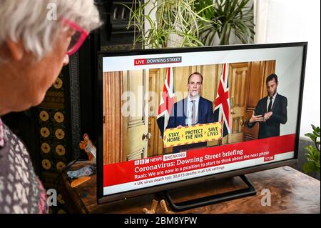 Dominic Raab gibt die täglich im Fernsehen übertragene Coronavirus Downing Street Briefing, beobachtet von einem Zuschauer. "Bleib zu Hause, beschütze den NHS, rette Leben" -Banner. Stockfoto