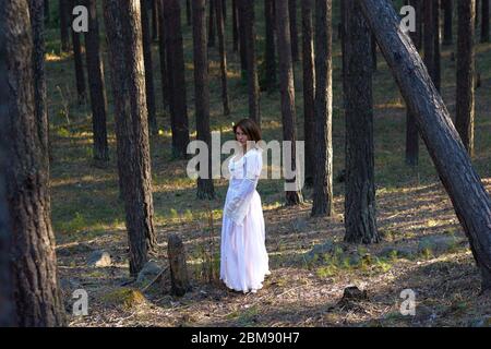 Mädchen in einem weißen Kleid im Wald bei Sonnenuntergang Stockfoto