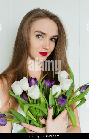 Ein schönes Mädchen hält einen großen Strauß. Ein Mädchen mit einem Strauß Tulpen. Stockfoto