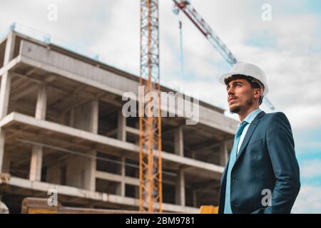 Junger männlicher Bauingenieur oder Geschäftsmann macht Schatten, indem er seine Hand in die Luft, Türkei, Bauingenieur, Bauplan hebt Stockfoto