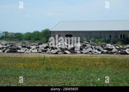 Stapel von Betonplatten, die in der Nähe des alten Gebäudes aufstapelt sind. Stockfoto