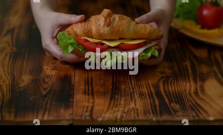 Aus nächster Nähe sehen Sie den Konditormeister, der frischen Croissant-Sandwich-Schinken und Käse auf der Holztheke serviert Stockfoto
