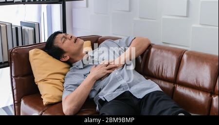 Ältere asiatische Menschen arbeiten hart, bis sie gestresst werden und er fühlt sich schlecht auf seinem Herzen Stockfoto