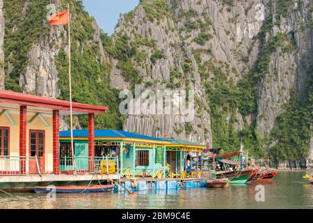Halong Bay Vietnam - Oktober 21 2013; bunte Häuser von Fischern Menschen über Wasser gegen Felswände mit Fischerbooten gebunden alonside gebaut. Stockfoto