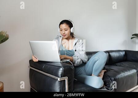 Eine junge Asiatin, die einen Computer im Wohnzimmer benutzt Stockfoto