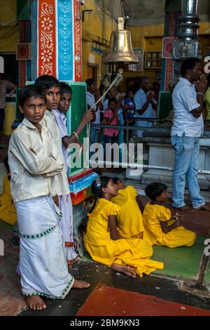 Hindu-Jungen läuteten eine zeremonielle Glocke während Puja (Gebete) innerhalb des Koneswaram Kovil in Trincomalee in Sri Lanka. Stockfoto