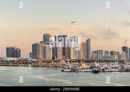 Miami, FL, Vereinigte Staaten - 27. April 2019: Skyline von Miami City bei Sonnenaufgang von Dodge Island in Biscayne Bay aus gesehen. Lange Verkehrsbrücke und Luxusyacht i Stockfoto