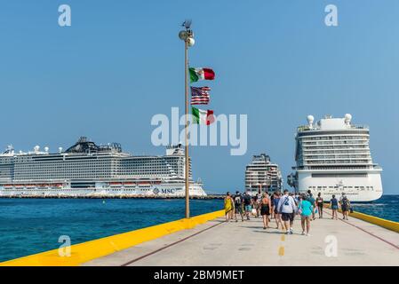 Costa Maya, Mexiko - 25. April 2019: Drei Kreuzfahrtschiffe nebeneinander mit Passagieren kehren zu Schiffen im Hafen von Costa Maya zurück. Flaggen von Mexiko, USA und Ita Stockfoto