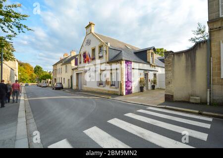 Touristen und Einheimische gehen eine neuere Straße entlang, gegenüber einem Hotel in Bayeux, Frankreich Stockfoto