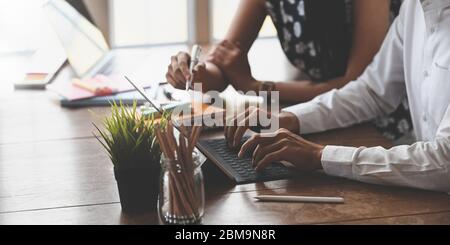 Zugeschnittenes Bild von Marketing-Team mit einem Stift und tippen auf Computer-Tablet mit Tastatur-Hülle während sitzen und arbeiten zusammen am Holz Stockfoto