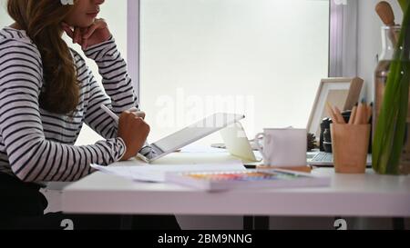 Cropped Shot kreative Frau mit einem Stift zeichnen auf Computer-Tablet mit Tastatur-Hülle, die auf Arbeitstisch setzen, während in geordneten sitzen Stockfoto