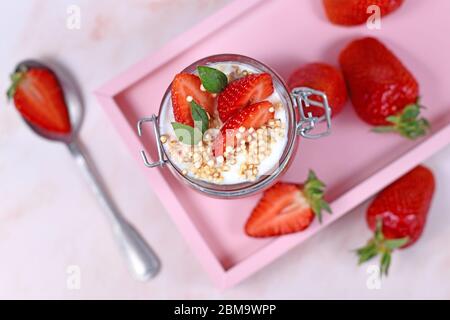 Draufsicht der gesunden Erdbeer-Obst-Dessert mit Joghurt und gepufften Quinoa-Körner auf rosa Tablette Stockfoto