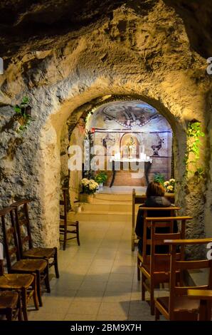 Budapest, Ungarn - 6. November 2019: Innenraum der Gellert-Höhlenkirche, Sziklatemplom. Felsenkirche in der ungarischen Hauptstadt. Person, die auf dem Stuhl vor dem Altar sitzt. Stockfoto