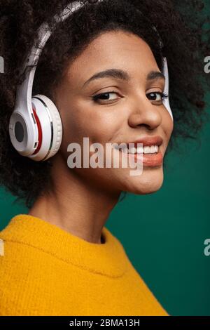 Seitenansicht Porträt einer lächelnden jungen afrikanischen Frau trägt Pullover isoliert über grünem Hintergrund Stockfoto