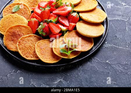 Haferflocken süße Pfannkuchen mit Erdbeeren und Honig auf einem schwarzen Teller auf einem Betontisch, gesundes Essen, horizontale Ansicht von oben, Freiraum, close-U Stockfoto