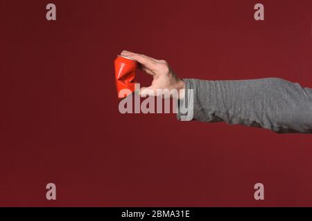 Hand zerquetschen eine Dose Getränk auf rotem Hintergrund Stockfoto