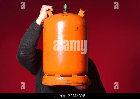 Mann, der eine Flasche Butangas auf rotem Hintergrund hält Stockfoto